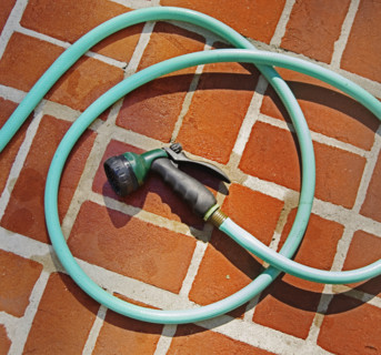Closeup of garden hose and brick floor.