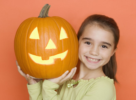 Smiling girl holding a jack o lantern.