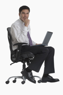 Businessman holding laptop in chair.