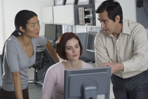 Office workers conferring at computer.