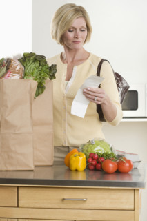 Woman checking grocery receipt.