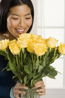 Woman arranging flowers in vase.