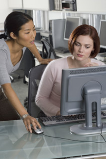 Office workers conferring at computer.