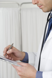 Doctor writing on chart.