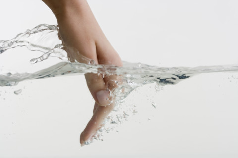 Hand dipping into water.