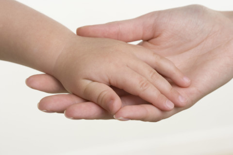 Baby holding hands with mother.