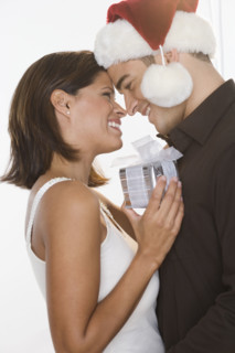 Man in Santa hat giving gift to woman.
