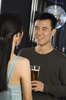 Man with beer talking to woman in nightclub.