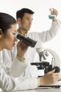Scientists with beaker and microscope.