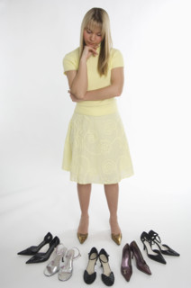 Studio shot of woman looking at many pairs of shoes.