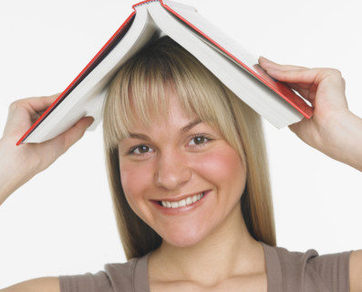 Studio shot of woman holding a book over her head.