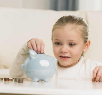 Young girl putting change in piggy bank.