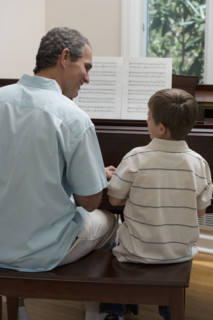 Father and young son playing piano.