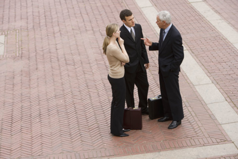 Three business people talking outdoors.