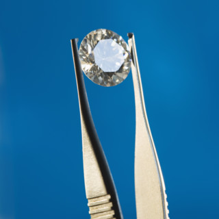 Clear gem held up by tweezers.