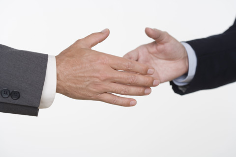 Businessmen about to shake hands.
