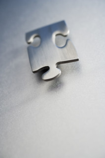 Angled metallic jigsaw puzzle piece .