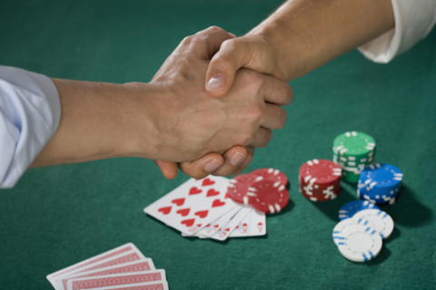Two men shaking hands over poker game.