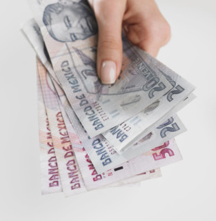 Close up studio shot of woman's hand holding Mexican money.