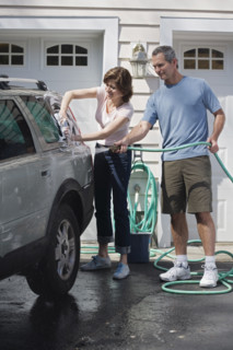 Couple washing car in driveway.