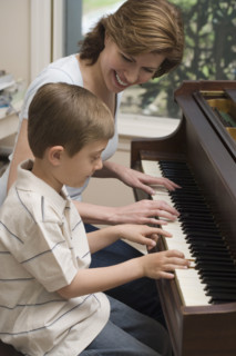Mother and young son playing piano.