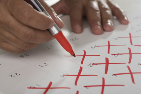 Close up of man crossing out days on calendar.