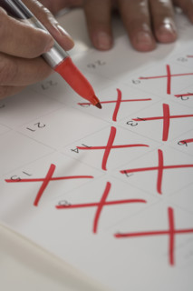 Close up of man crossing out days on calendar.