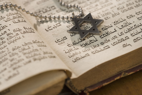 Star of David necklace on book with Hebrew text.