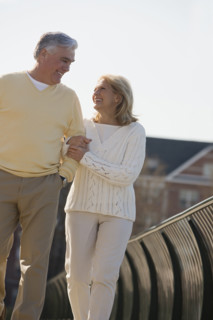 Senior couple walking arm in arm outdoors.