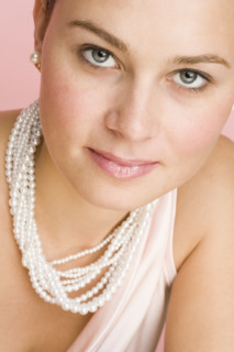 Close up of woman wearing pearls.