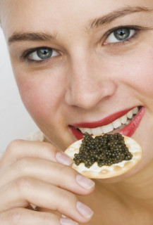 Close up of woman eating caviar on a cracker.