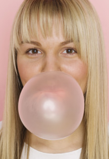Close up of woman blowing bubble with bubble gum.