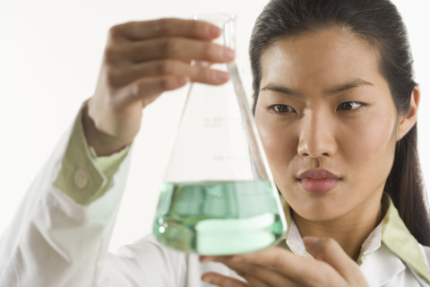 Scientist looking at glass beaker.