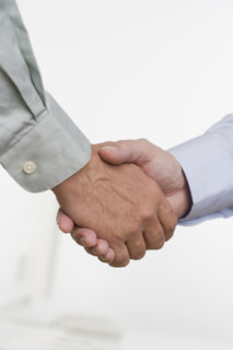 Men in shirtsleeves shaking hands.