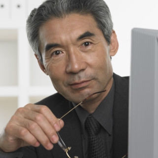 Senior Asian businessman holding eyeglasses.