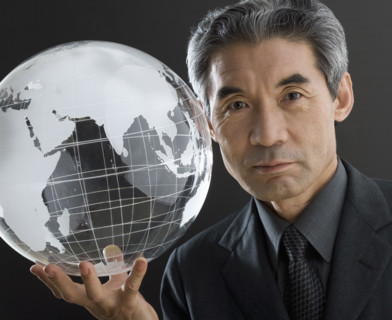 Senior Asian businessman holding clear globe.