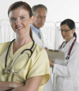 Female doctor smiling with doctors in background.