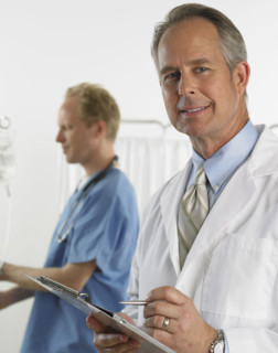 Male doctor smiling and holding chart.