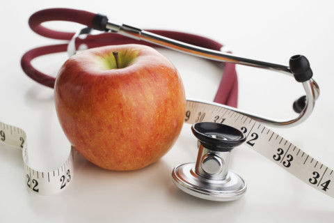 Close up of apple, tape measure and stethoscope.