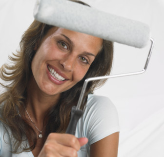 Woman smiling and holding paint roller.
