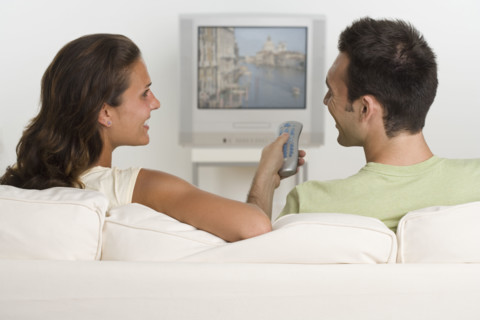Couple sitting on sofa watching television.