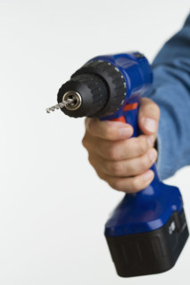 Close up studio shot of man holding cordless drill.