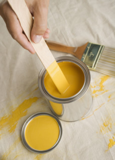 High angle view of man stirring paint in paint can.