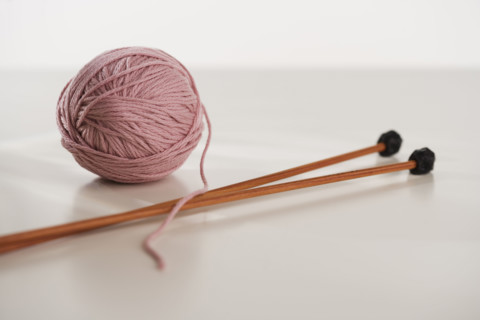 Close up studio shot of ball of yarn and knitting needles.