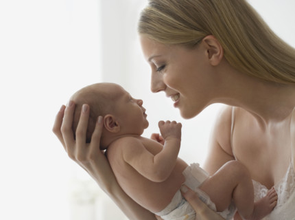 Mother smiling at newborn baby.