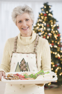 Senior woman holding tray of Christmas cookies.