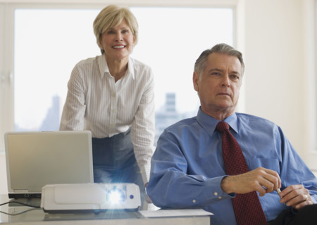 Senior businesspeople using projector in conference room.
