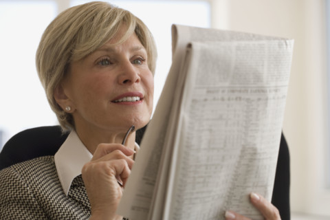 Senior businesswoman reading newspaper.