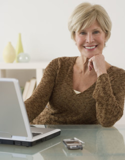 Portrait of senior woman next to laptop.