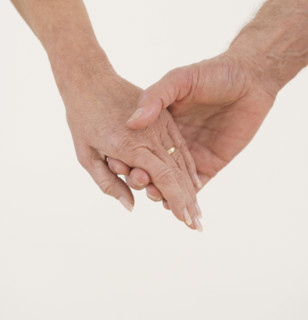 Close up of senior couple holding hands.
